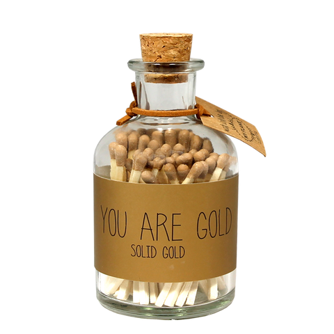 Streichhölzer gold. Eine durchsichtige Flasche mit Korkdeckel. Auf der Flasche ist eine Beschriftung you are gold solid gold.