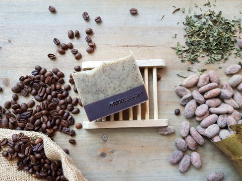 Naturseife mit Kaffee Pfefferminze Bio Kakaopulver auf einer Seifenablage aus Holz und Kaffebohnen.