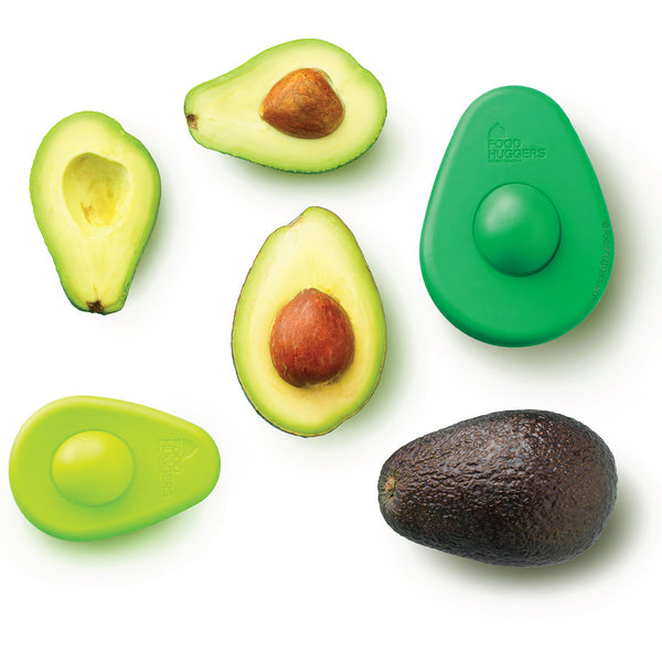 Eine ganze Avocado, zwei halbe Avocados mit dem Kern, eine halbe Avocado ohne Kern, ein hell grünes kleines Avocado Hugger und ein grünes großes Avocado Hugger.