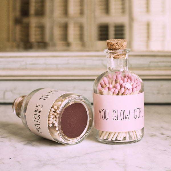 Zwei durchsichtigen Flaschen mit Streichhölzern rosa und Korkdeckel. Auf der Flasche ist eine Beschriftung "You glow girl"